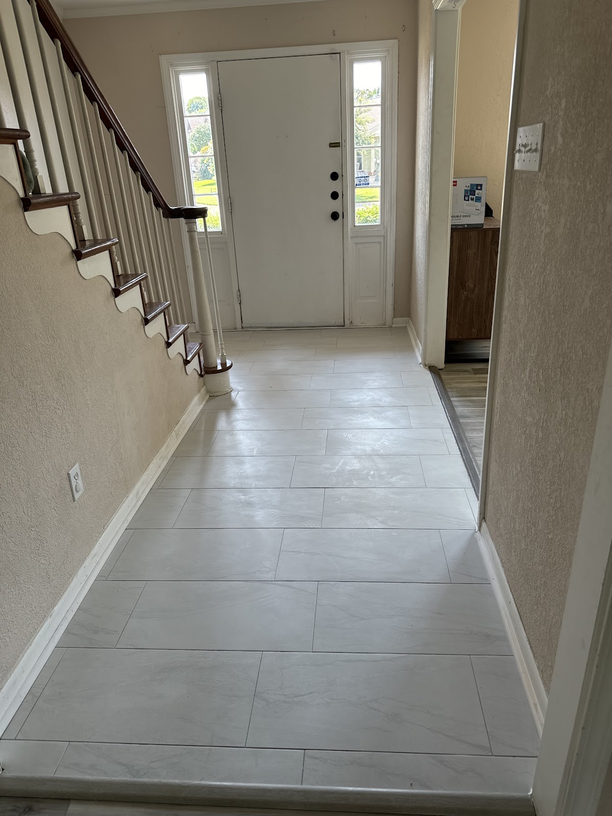 New tile flooring in an entryway with staircase
